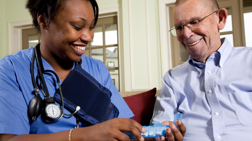 Nurse offering medication to old man.